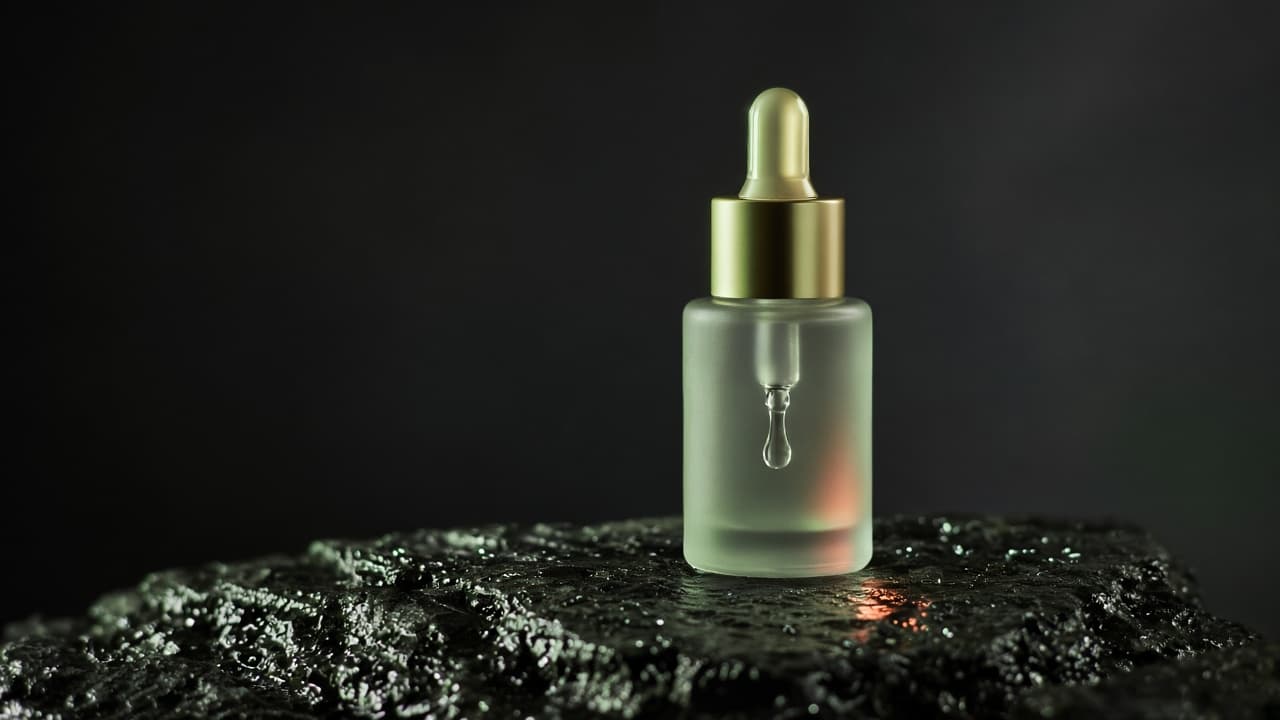 分鏡定格：深色石面上的精華液滴管瓶